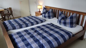 A double bed with blue and white checkered bedding, a wooden headboard, and a bedside table with a lamp. - Landgasthaus zum Seysingshof (Heldburger Unterland)
