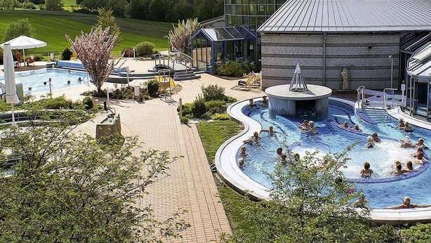 A resort with a large swimming pool, lounge areas, and a building with a modern design. - Landgasthaus zum Seysingshof (Heldburger Unterland)