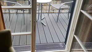 A view from inside a room to an outdoor patio area with a table and two chairs. - Landgasthaus zum Seysingshof (Heldburger Unterland)