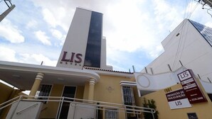 A building with a prominent 'LIS' sign on the facade, a staircase leading to the entrance, and a signboard advertising property sales. - Lis Hotel (Teresina)