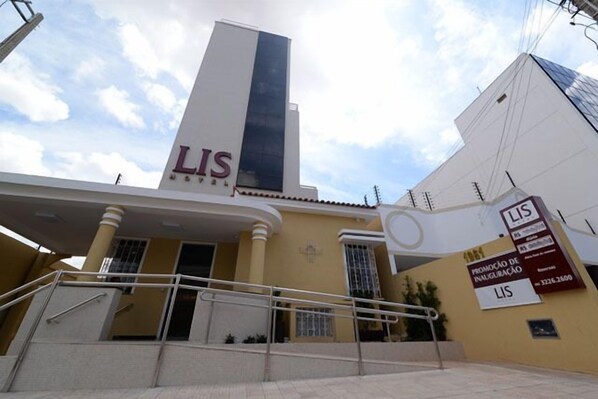 A building with a prominent 'LIS' sign on the facade, a staircase leading to the entrance, and a signboard advertising property sales. - Lis Hotel (Teresina)