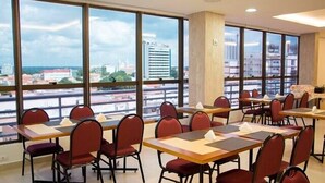 A conference room with multiple tables and chairs, large windows offering a city view. - Lis Hotel (Teresina)