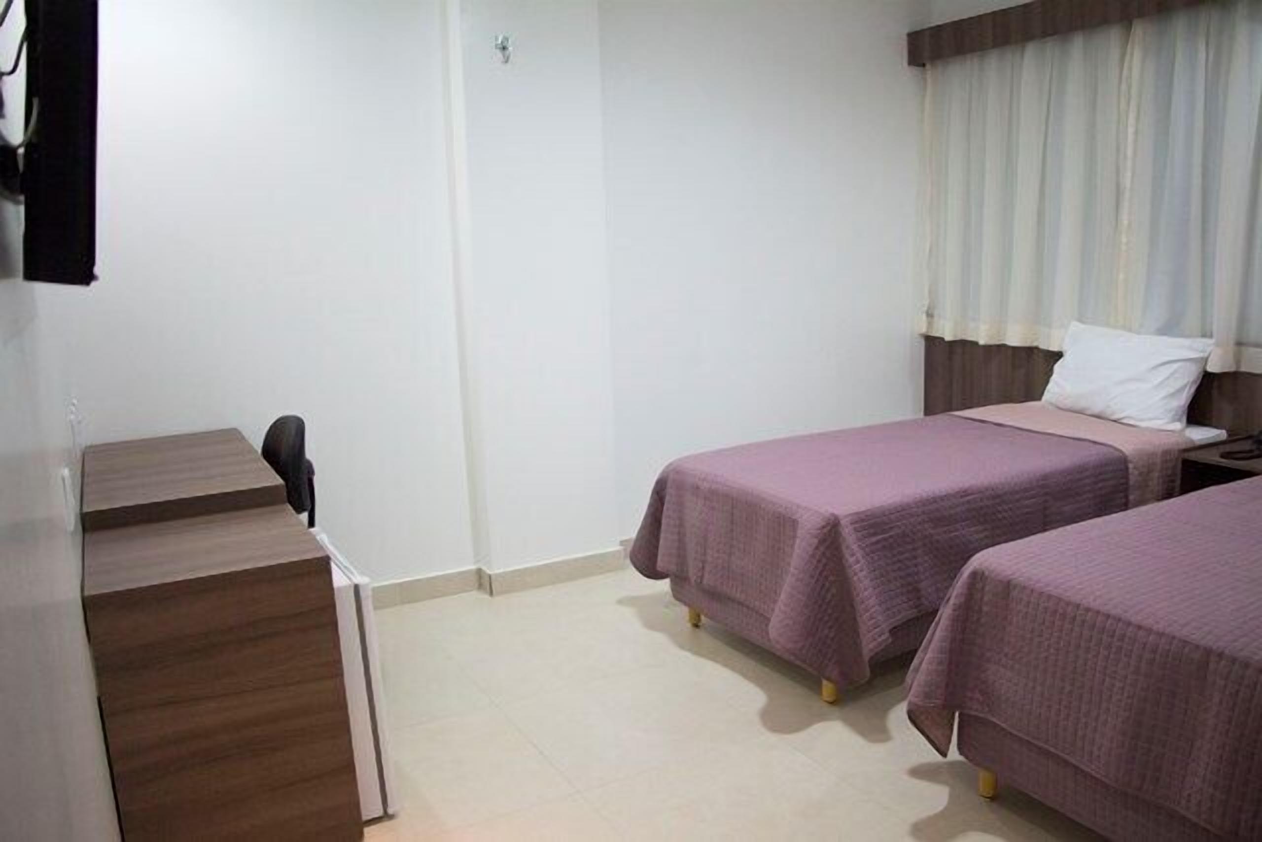 Une chambre d’hôtel avec deux lits, un bureau et une chaise.