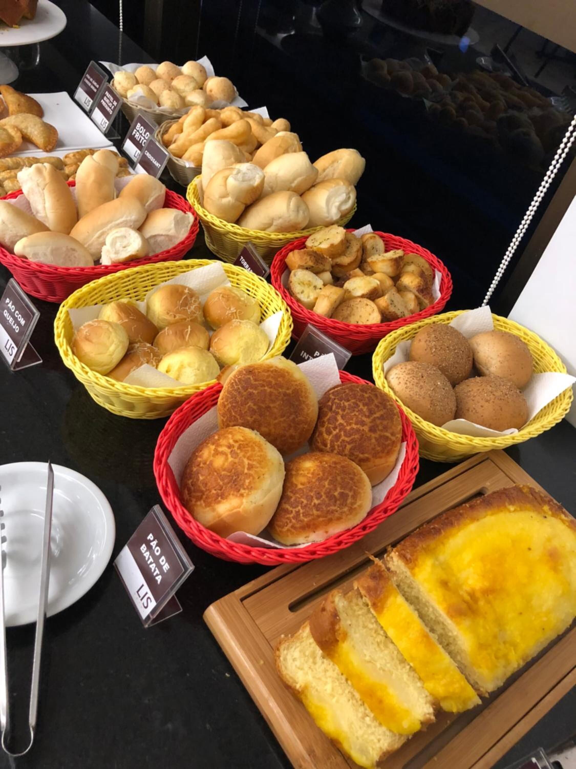 Une table de buffet proposant une variété de pains et de viennoiseries, notamment des petits pains, des brioches et des grissinis, présentés dans des paniers.