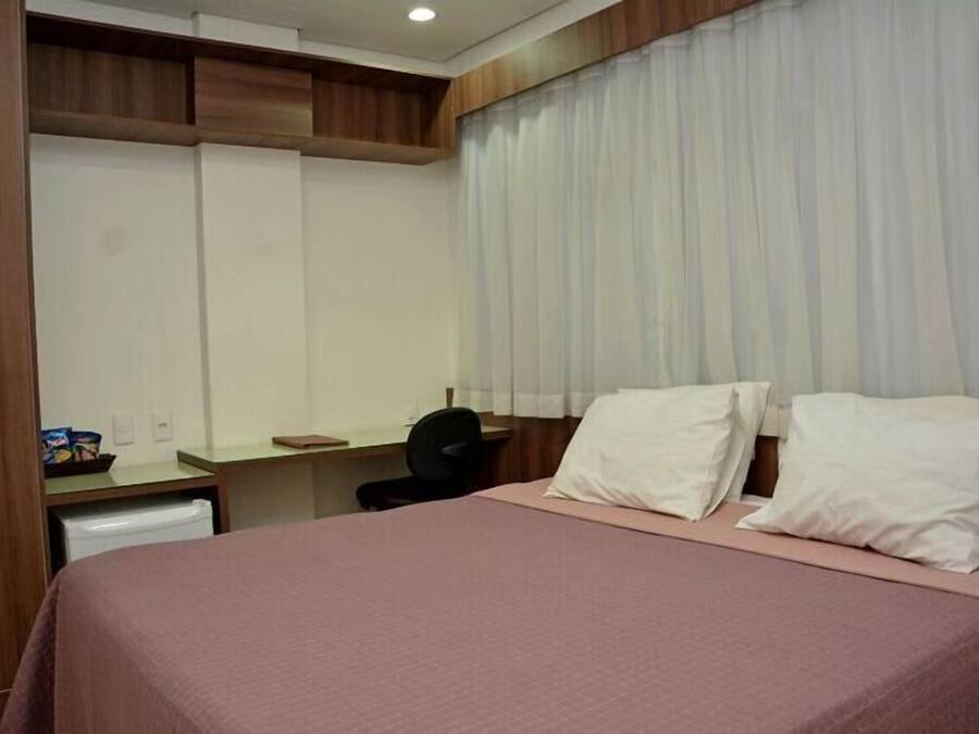 Una habitación de hotel con una cama, un escritorio y una silla.