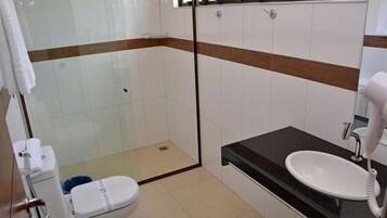 Un baño con inodoro, ducha con cerramiento de vidrio, lavamanos y secador de pelo.