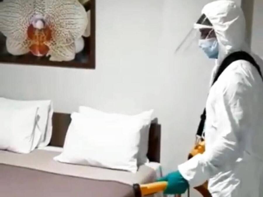 Una persona con traje blanco protector rociando una habitación.
