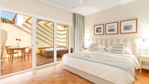 Une chambre d’hôtel comprenant un lit, une petite table avec des chaises, un jacuzzi et une porte-fenêtre coulissante donnant sur un espace extérieur.