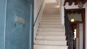 A staircase with a blue door on the left and a wooden door at the bottom. - Mario Apartment 5012 (Venice)