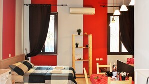 A room with a bed, a wooden chair, a table with a red tablecloth, and a shelf with plants. - Mario Apartment 5012 (Venice)