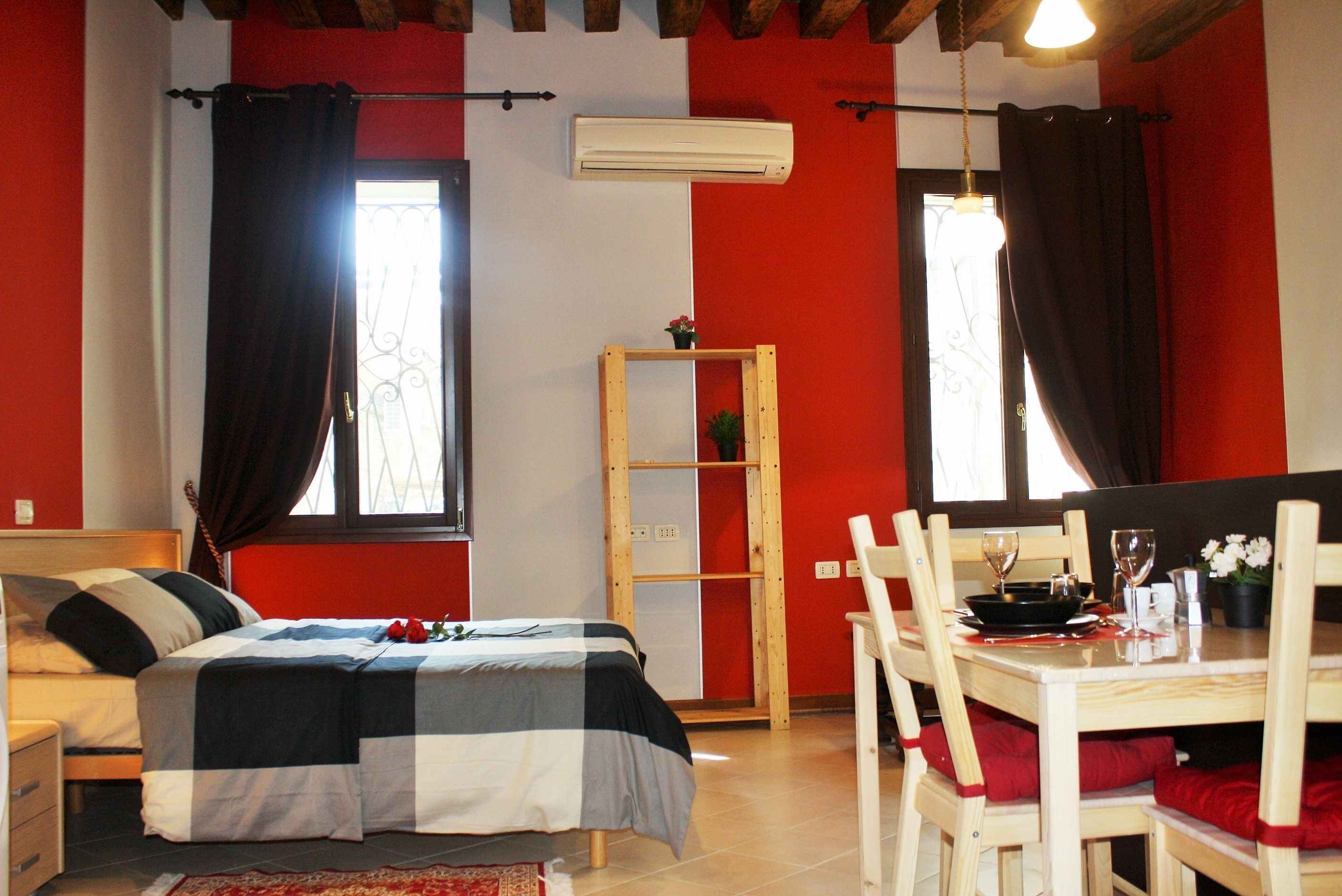 Une chambre à coucher comprenant un lit, une armoire en bois, une table à manger avec des chaises et un appareil de climatisation.