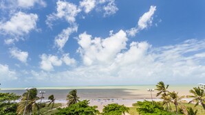 Una playa con cielo despejado, palmeras y mar tranquilo.