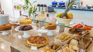 Un bufé con diversos alimentos, incluyendo pasteles, bollería y frutas.