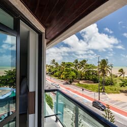 Enjoy stunning views of the beach from this balcony overlooking a palm-lined street.