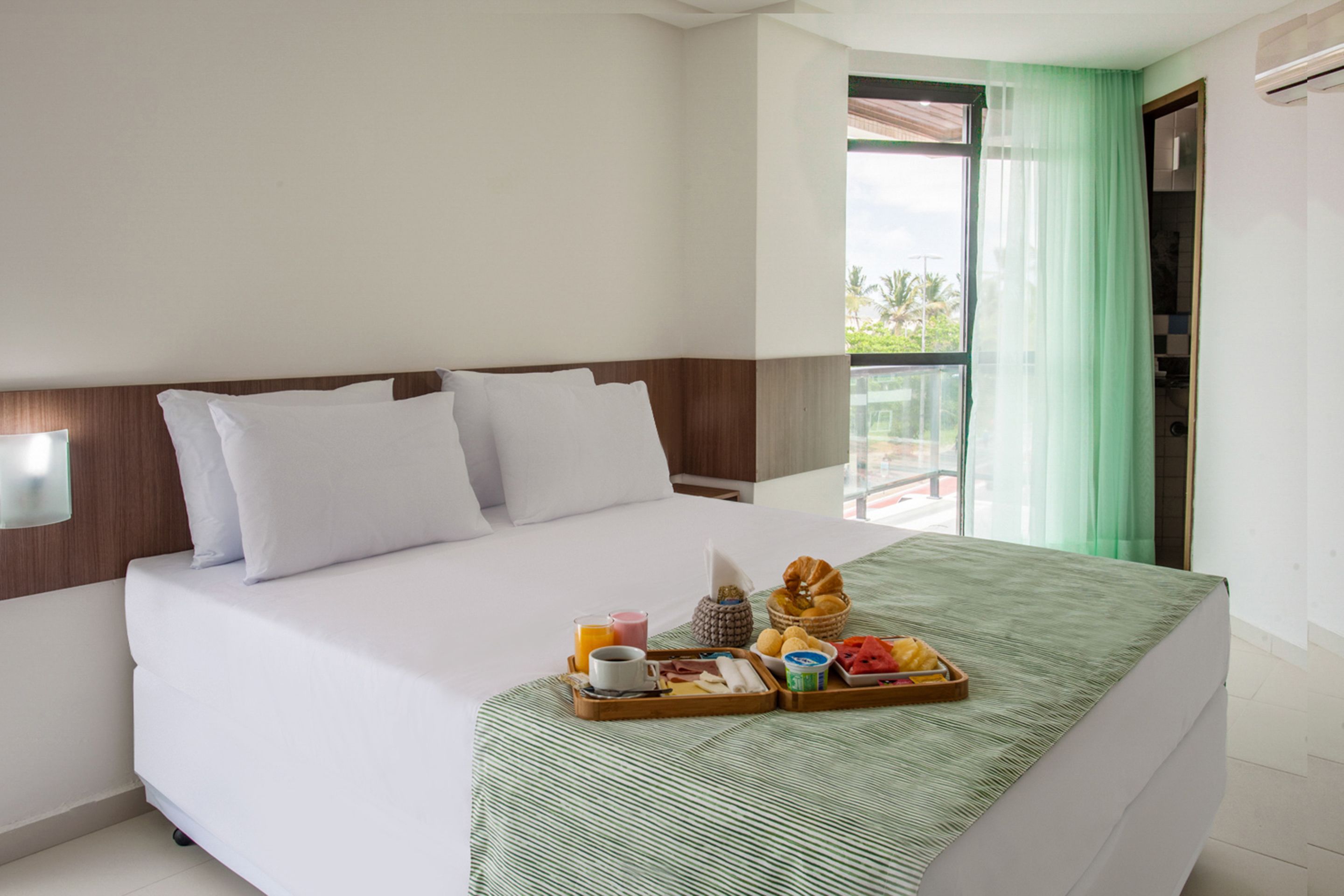 Une chambre d'hôtel avec un lit, un plateau de petit-déjeuner et une vue sur l'extérieur.