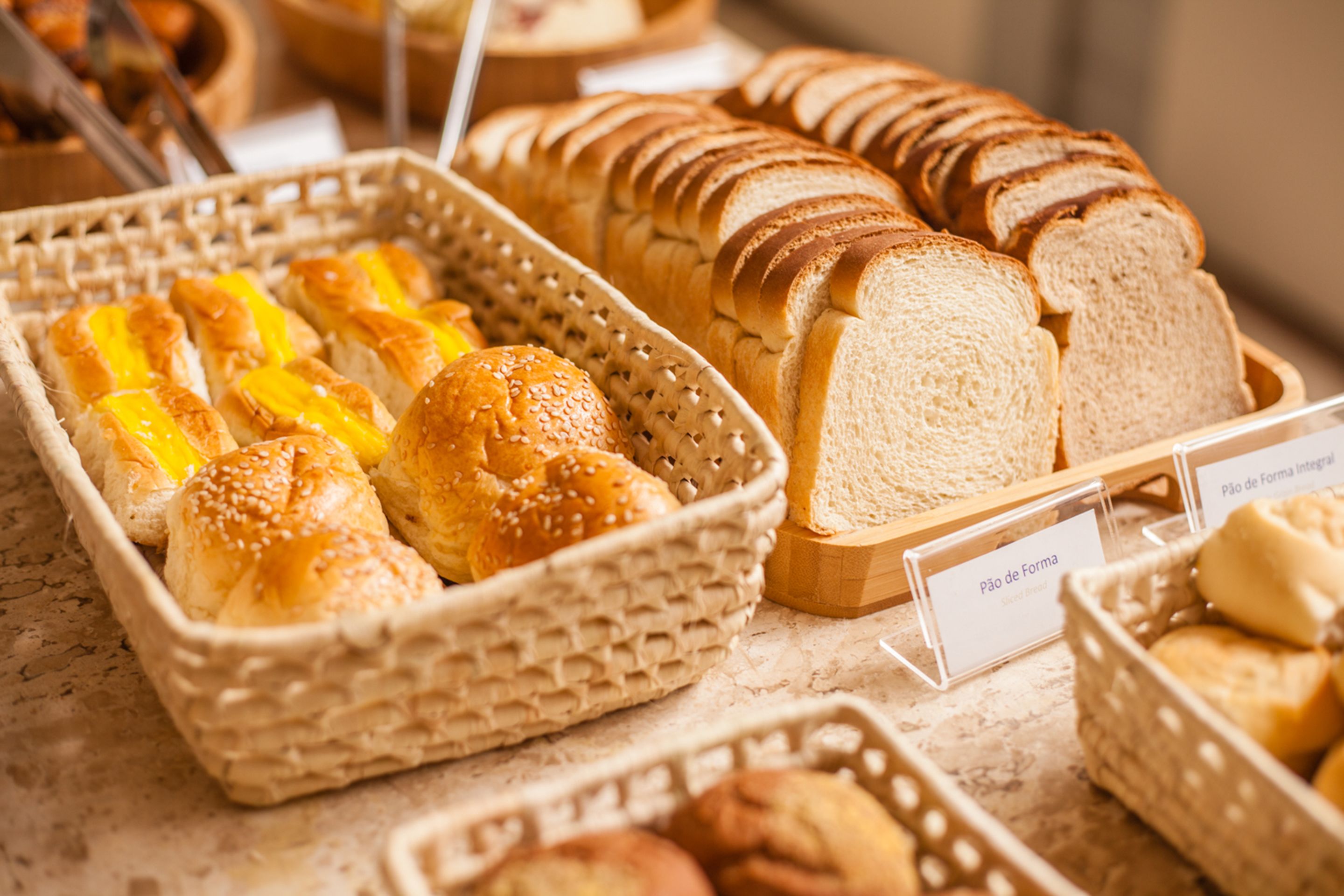 Variedad de panes y pasteles expuestos en cestas y sobre una barra.