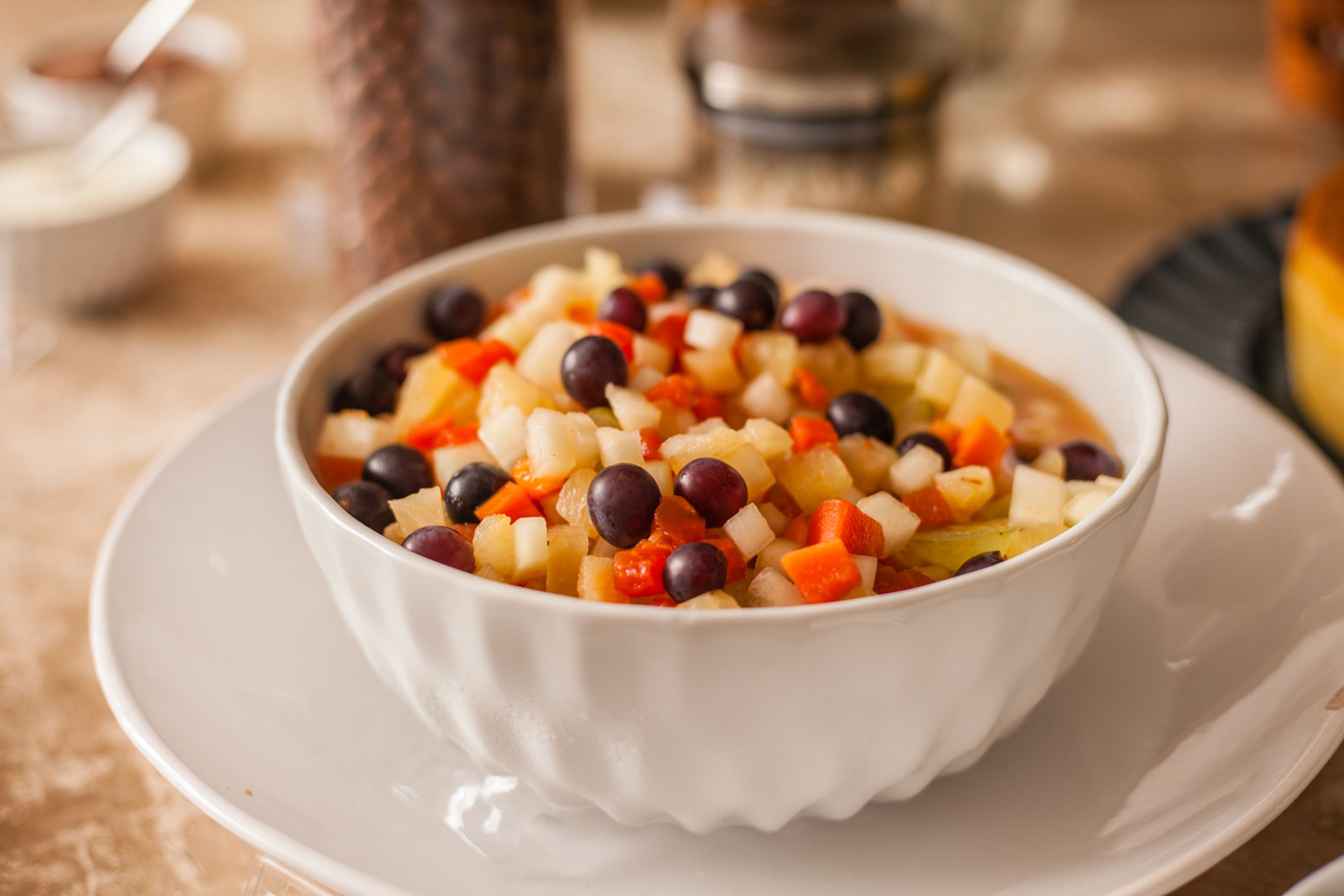 A bowl of mixed fruit salad on a white plate.