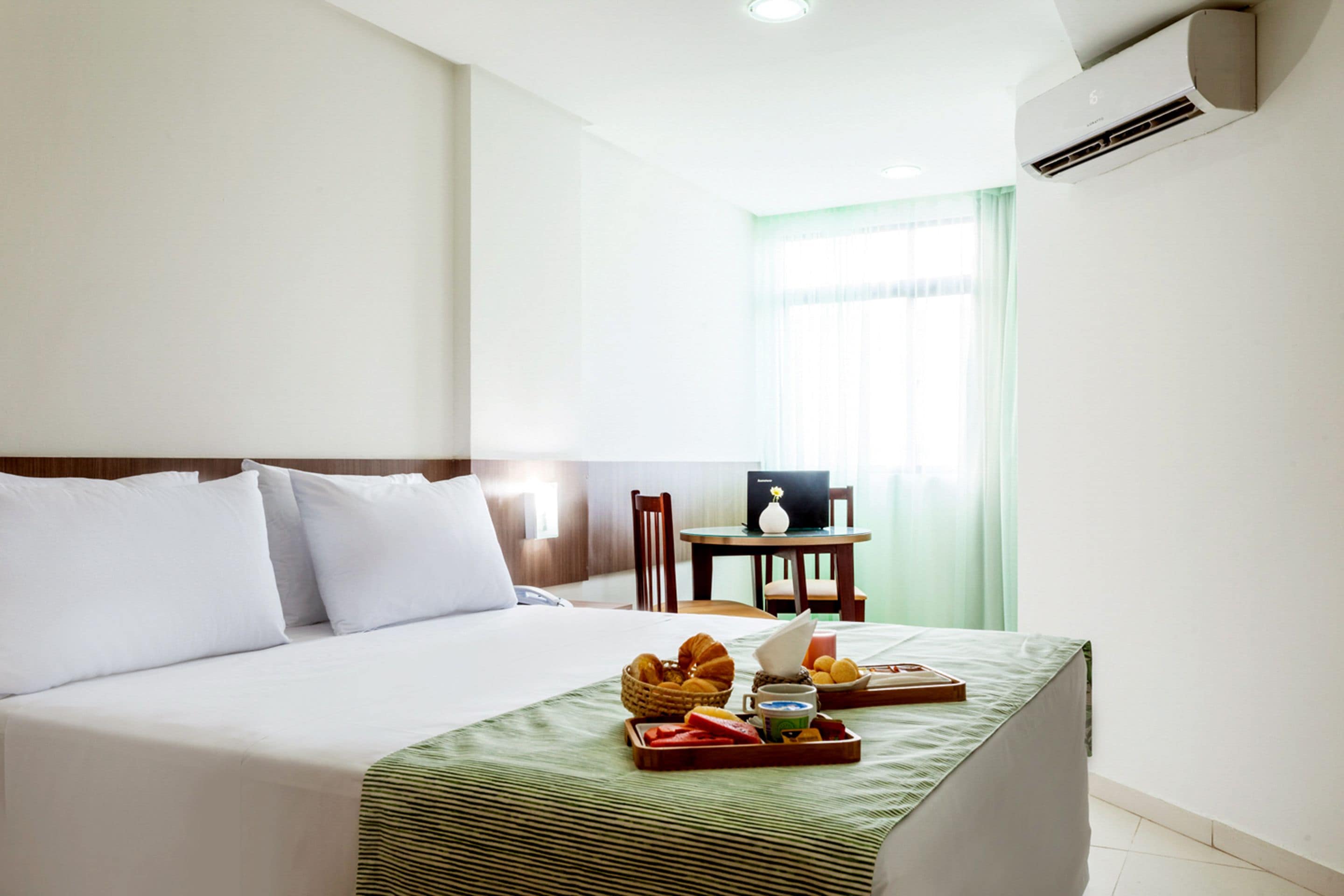 A hotel room with a bed, a desk, and a breakfast tray.