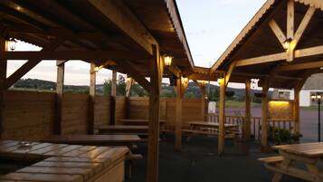Guests can enjoy the rustic pavilion, featuring benches and picnic tables, surrounded by the natural landscape.