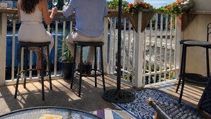 A couple dining at an outdoor table with a view of the sea, a flag, and a decorative bird statue. - The Ocean Guesthouse (Weymouth)