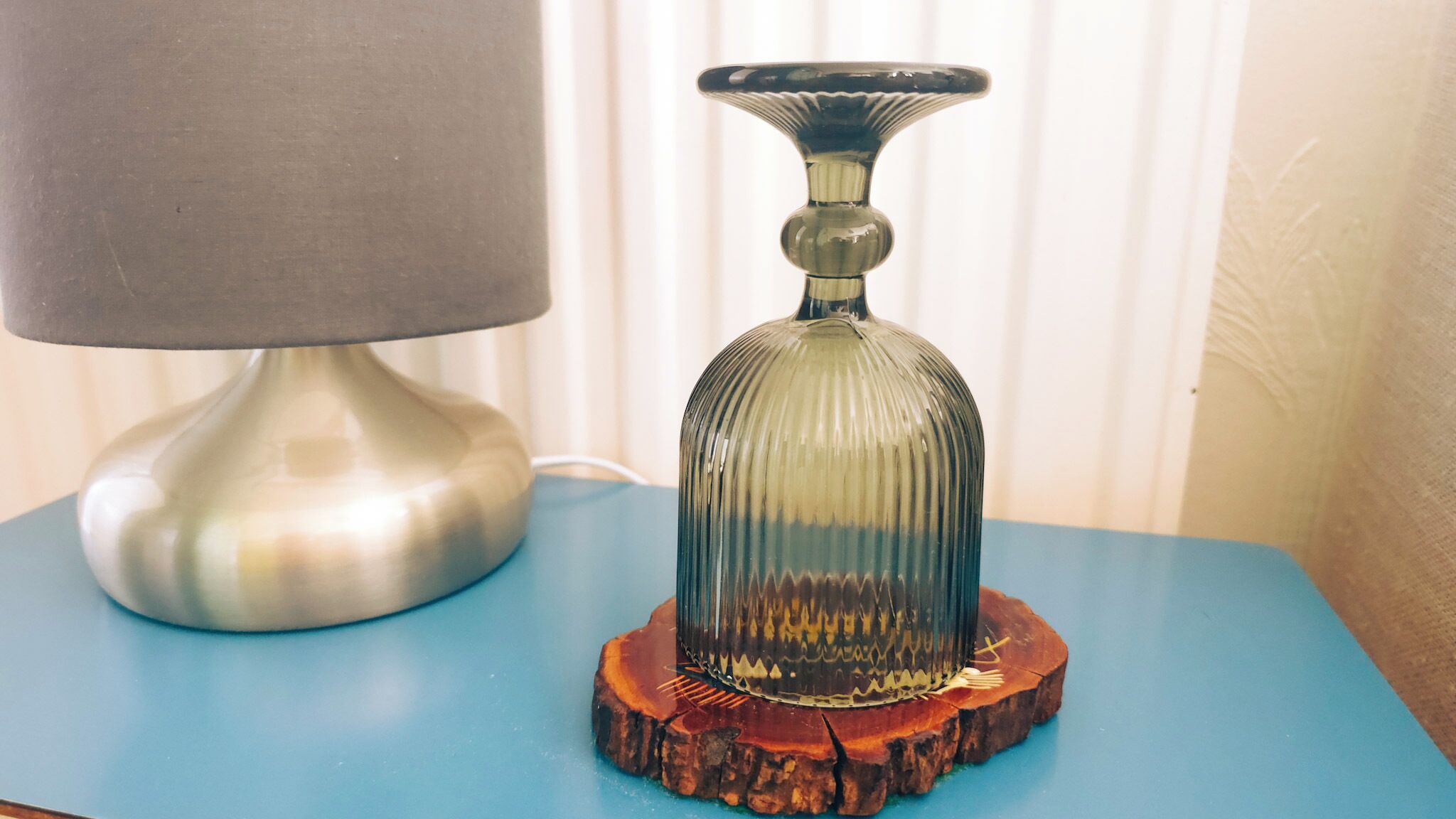 A lamp and a glass bottle on a wooden coaster.