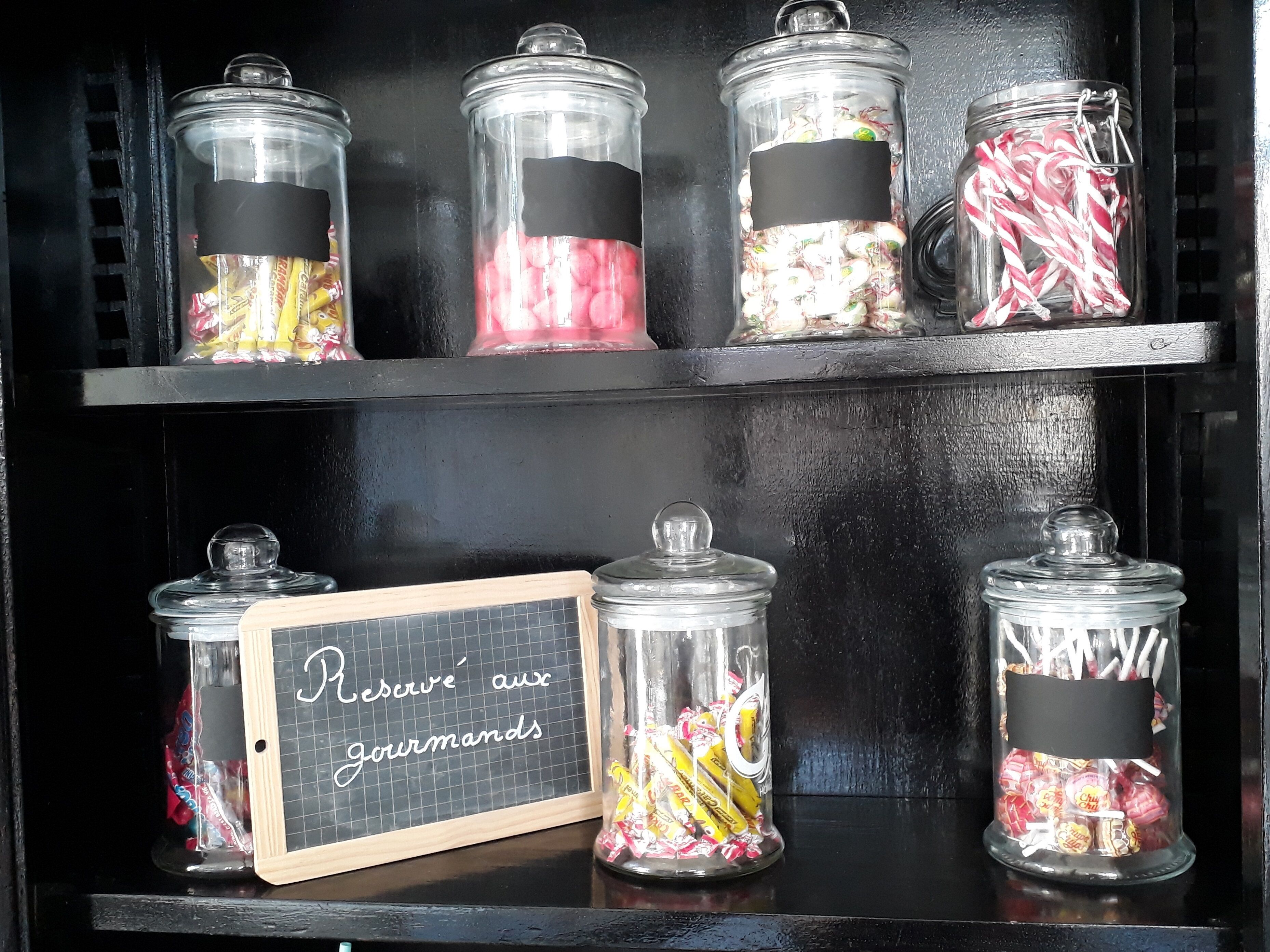 Prestatge amb envasos de vidre plens de diferents caramels i un cartell que diu "Reserve aux gourmandises".