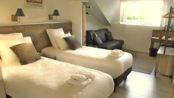 A hotel room with two beds, a desk, a chair, and a window with a view.