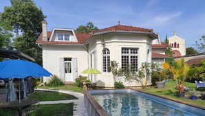 A house with a swimming pool, a patio with a table and chairs, and a garden with various plants. - Villa Glen-tara (Lanton)