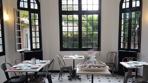 A dining area with tables set for two, black chairs, and a central table with a covered floral arrangement. - Villa Glen-tara (Lanton)