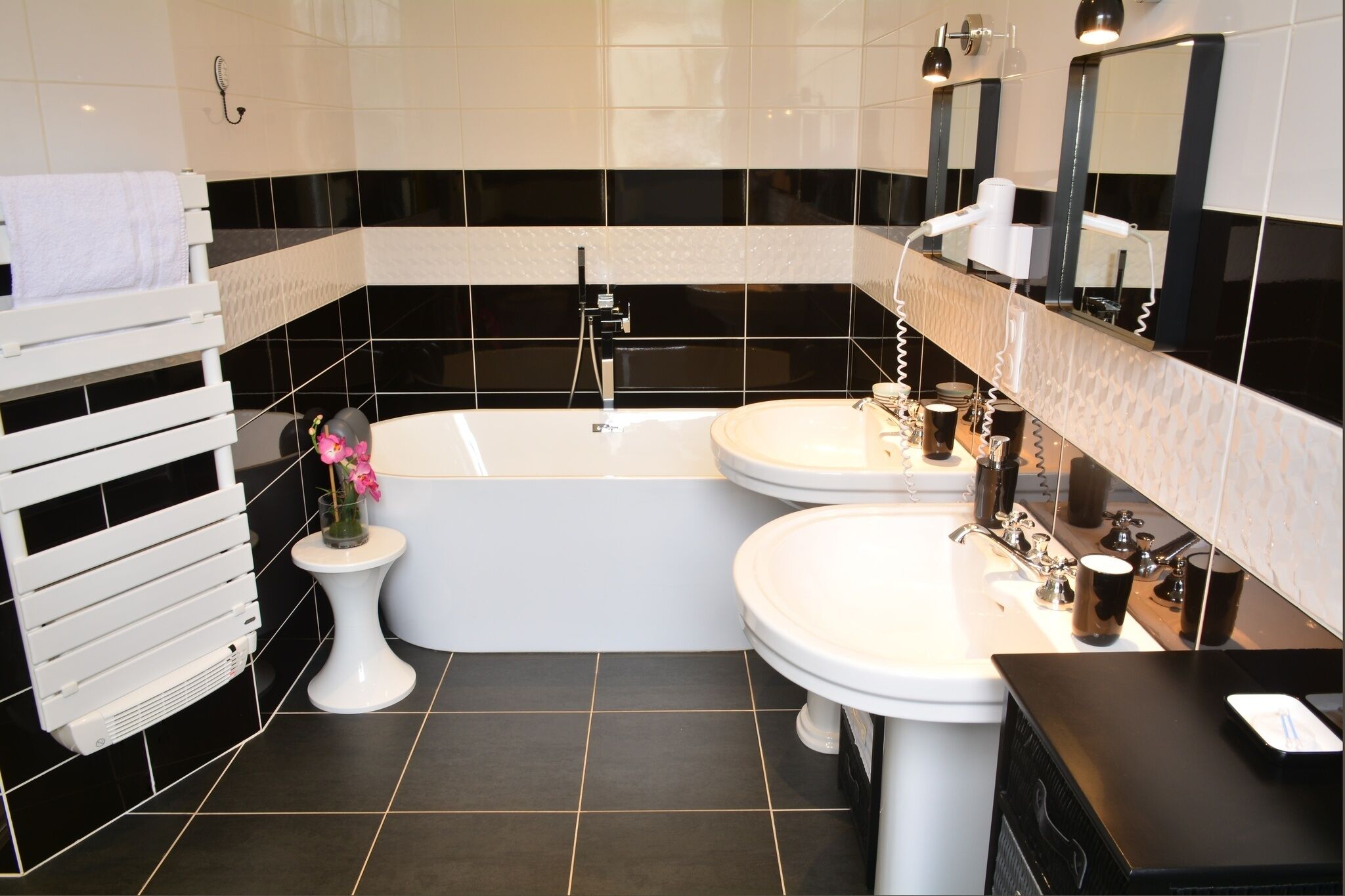 Een moderne badkamer met een bad, twee wastafels en een wastafelmeubel.