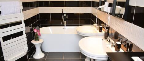 Een moderne badkamer met een bad, twee wastafels en een wastafelmeubel.