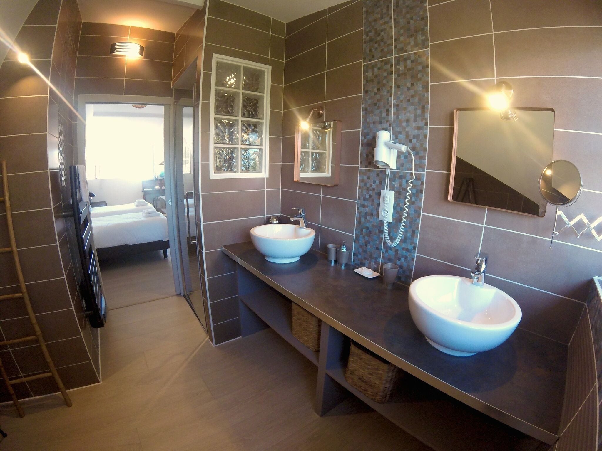 Ein modernes Badezimmer mit zwei großen Waschbecken, einem Fön und einem Spiegel.