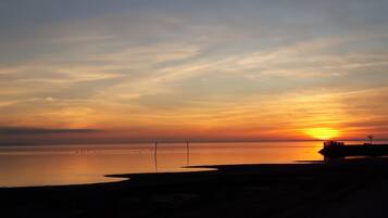 Un atardecer sobre una masa de agua tranquila con un muelle que se adentra en el agua.