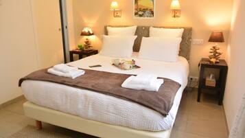A neatly made bed with white and brown linens, two bedside lamps, a tray with a teapot and cups, and a wall poster.