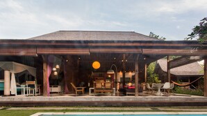A covered outdoor area with a pool, wooden furniture, and a hanging hammock.
