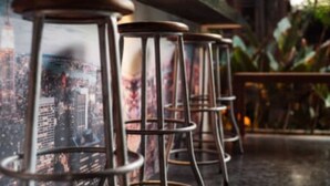 A bar area with metal stools and a cityscape mural on the wall.