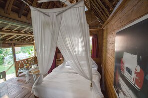 Ein Bett mit Baldachin, ein kleiner Tisch mit Stühlen und ein Poster an der Wand.
