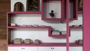 A room with a white wall, wooden paneling on one side, and pink shelving units.