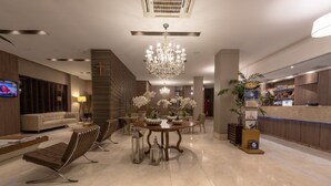 A modern lobby with a chandelier, a reception desk, and a seating area with a coffee machine. - Class Hotel Rio Claro (Rio Claro)