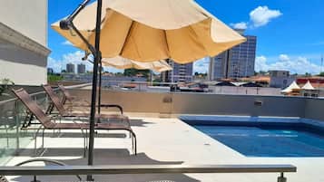 Una piscina al aire libre, sillones reclinables de piscina