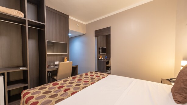 A hotel room with a bed, a desk, and a wardrobe. - Class Hotel Rio Claro (Rio Claro)