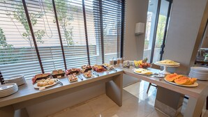 A buffet setup with various food items and utensils on a table, with a window in the background. - Class Hotel Rio Claro (Rio Claro)