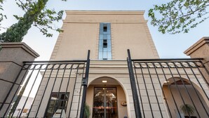 A hotel entrance with a beige facade, black metal gates, and a central arched doorway. - Class Hotel Rio Claro (Rio Claro)