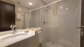 Un baño moderno con un espejo grande, un lavabo y una ducha con mampara de vidrio.