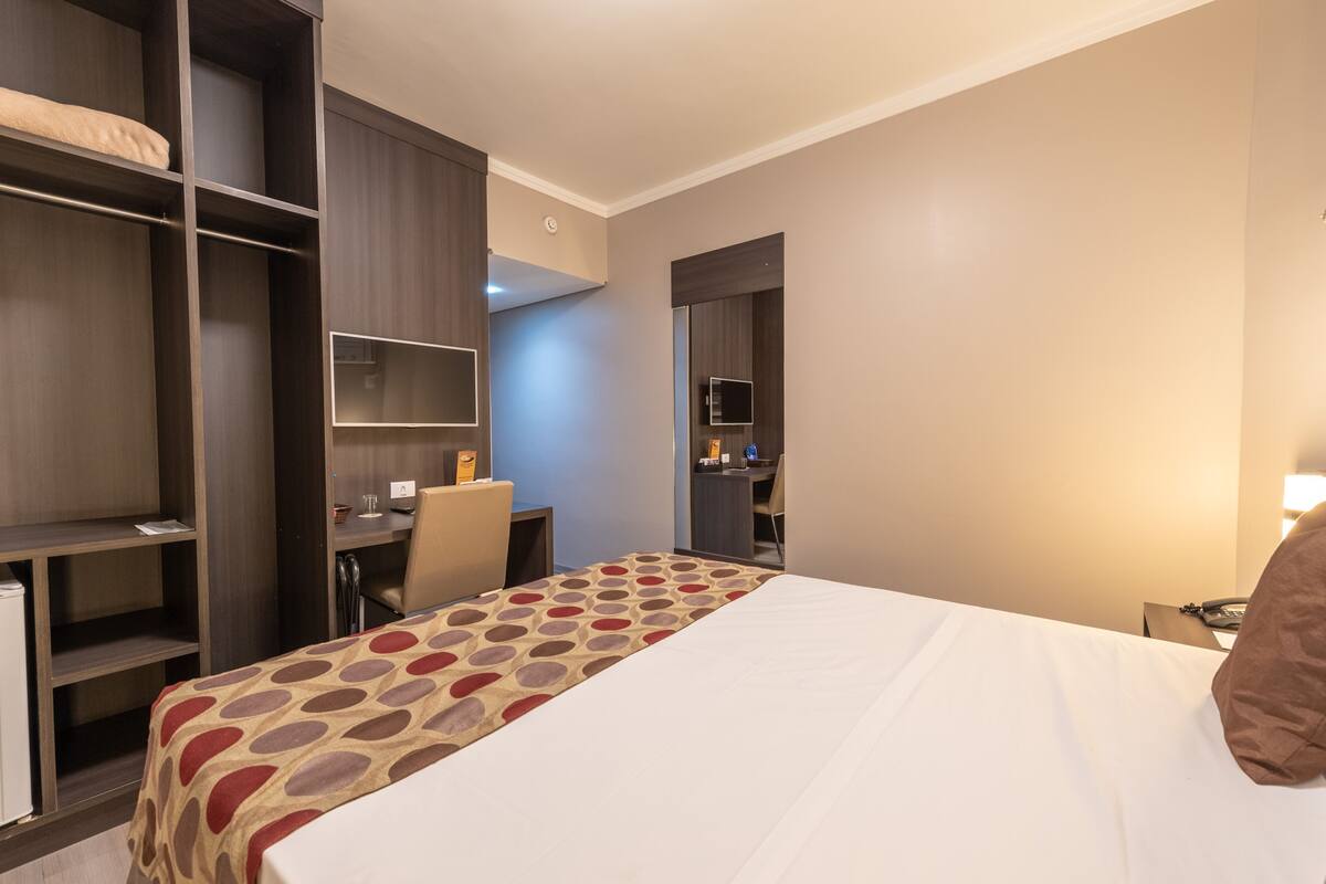 A hotel room with a bed, a desk, and a wardrobe.