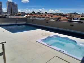 A rooftop pool area with a hot tub and a view of the cityscape.