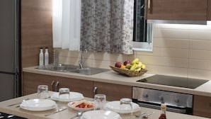 Una cocina con mostrador, lavamanos y estufa. Hay platos, utensilios y una cesta de frutas en el mostrador.