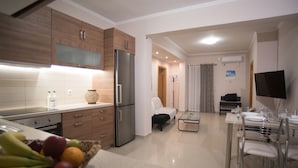 Una cocina moderna con alacenas de madera, un refrigerador de acero inoxidable y un comedor con una mesa y sillas de vidrio.