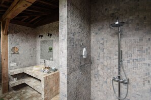 A bathroom with a tiled shower, a sink, and a mirror.