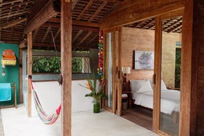 A wooden room with a bed, a hammock, and a potted plant.